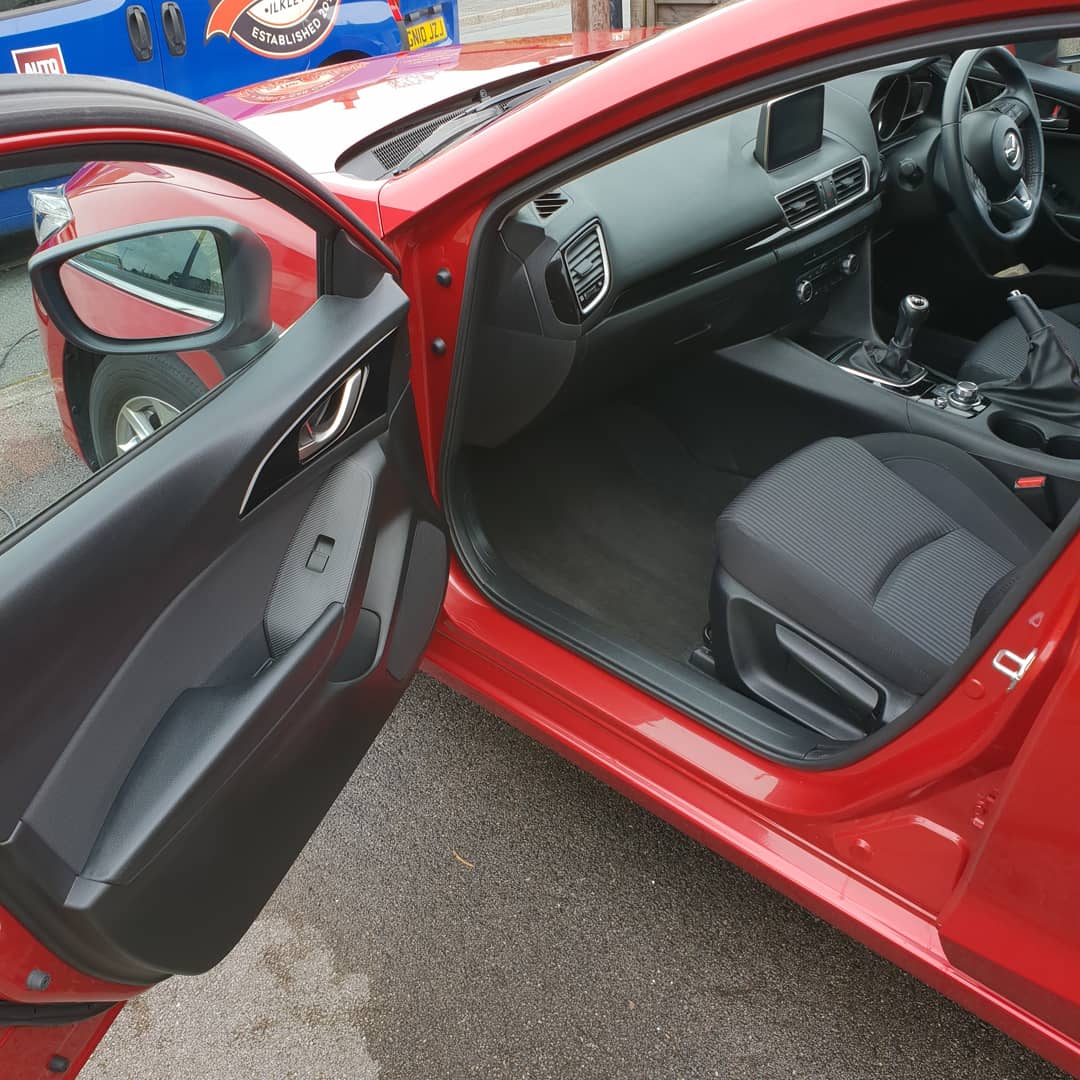 Red car with the door open showing its cleaned interior
